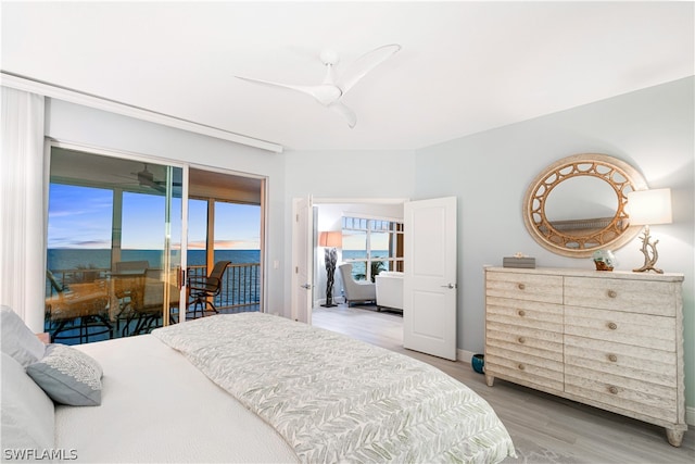 bedroom featuring a water view, light wood-type flooring, ceiling fan, and access to exterior