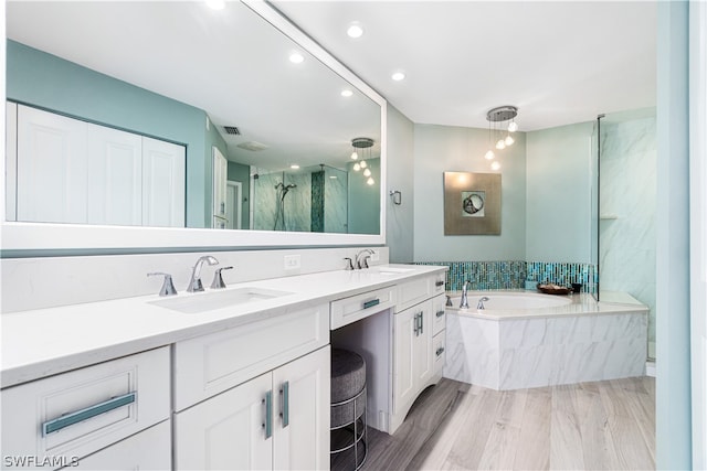 bathroom with hardwood / wood-style floors, dual bowl vanity, and separate shower and tub