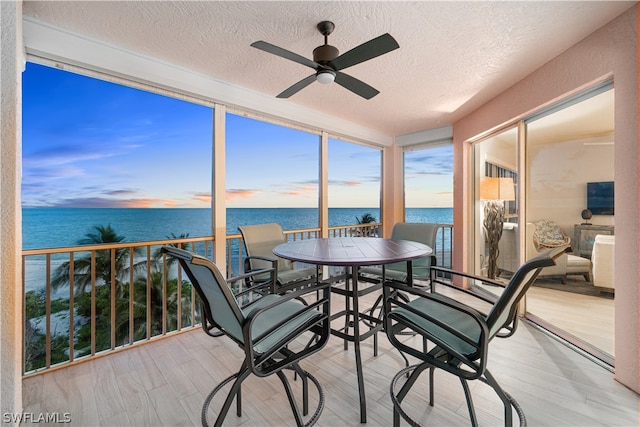 sunroom / solarium with a water view and ceiling fan