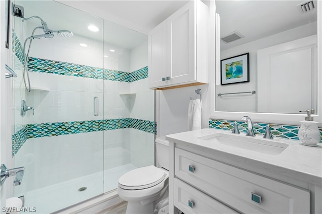 bathroom featuring vanity, a shower with door, and toilet