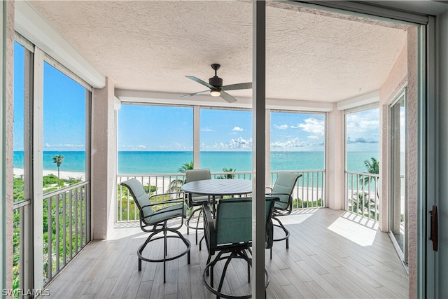 sunroom featuring a water view and ceiling fan