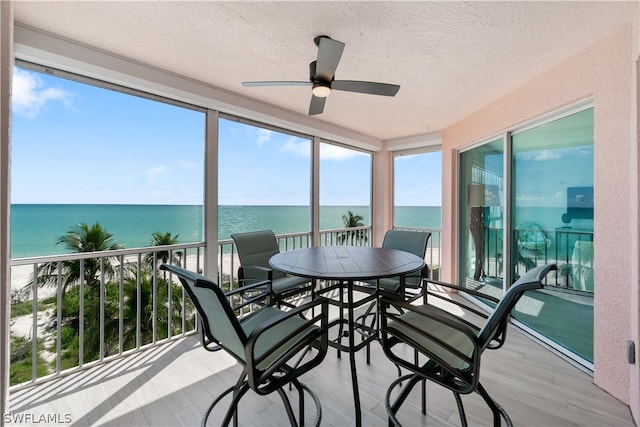 sunroom / solarium with a water view and ceiling fan