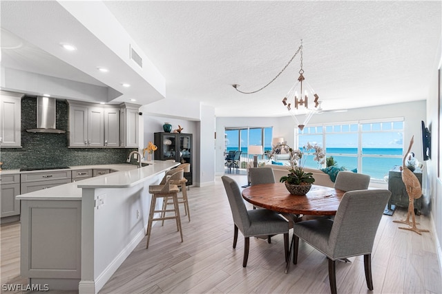 dining area with light hardwood / wood-style floors, a wealth of natural light, and an inviting chandelier