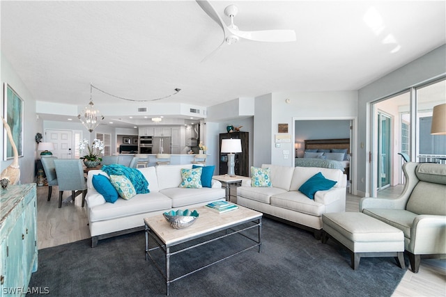 living room featuring ceiling fan with notable chandelier and wood-type flooring