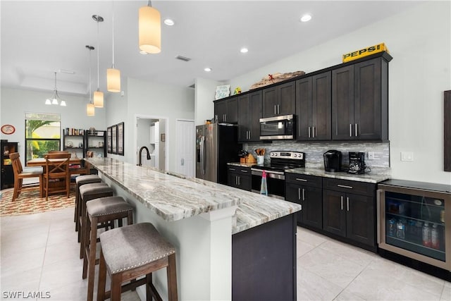 kitchen with decorative light fixtures, stainless steel appliances, beverage cooler, and a spacious island