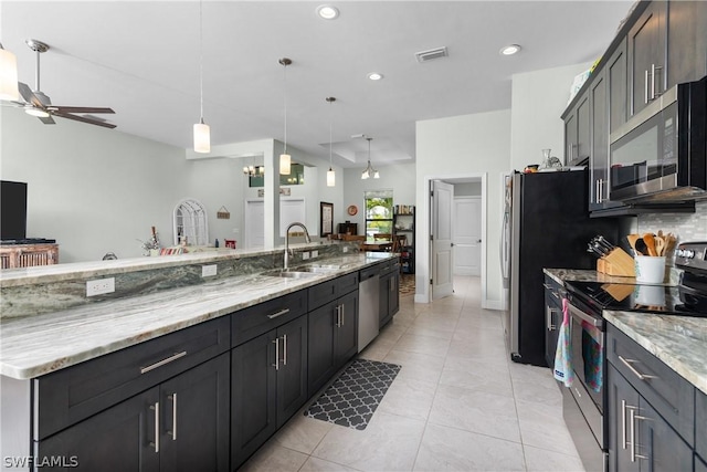 kitchen with appliances with stainless steel finishes, ceiling fan, sink, a large island with sink, and decorative light fixtures