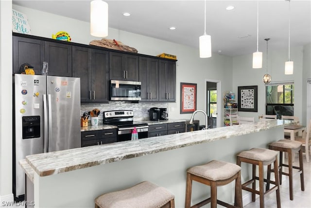 kitchen with a kitchen island with sink, a breakfast bar, decorative light fixtures, and appliances with stainless steel finishes