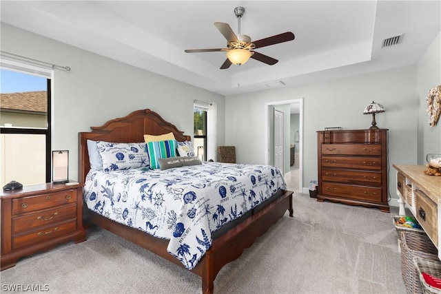 carpeted bedroom with a tray ceiling and ceiling fan