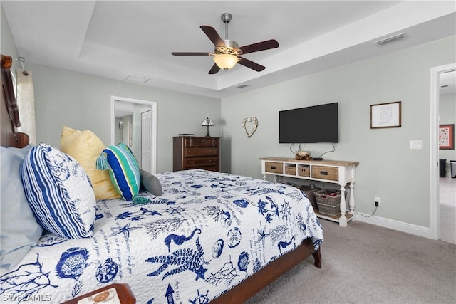 carpeted bedroom featuring ceiling fan and a raised ceiling