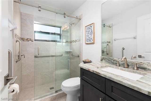 bathroom featuring vanity, toilet, and a shower with door