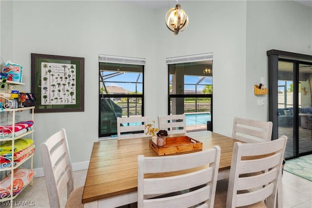 tiled dining area featuring a notable chandelier, a healthy amount of sunlight, and a high ceiling