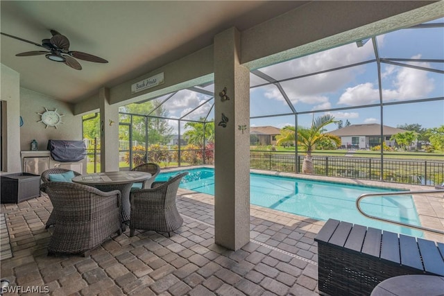 view of pool with glass enclosure, ceiling fan, and a patio area