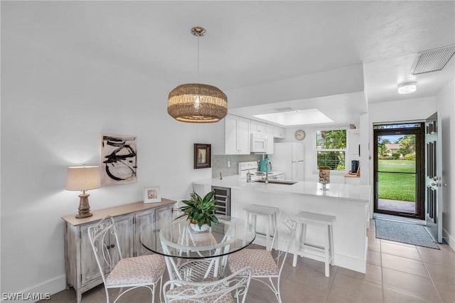 dining space featuring light tile patterned flooring, sink, and wine cooler