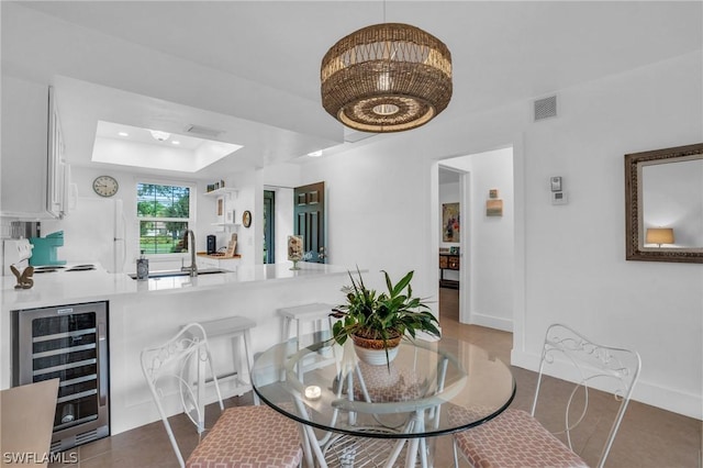 dining area with a tray ceiling, beverage cooler, and sink