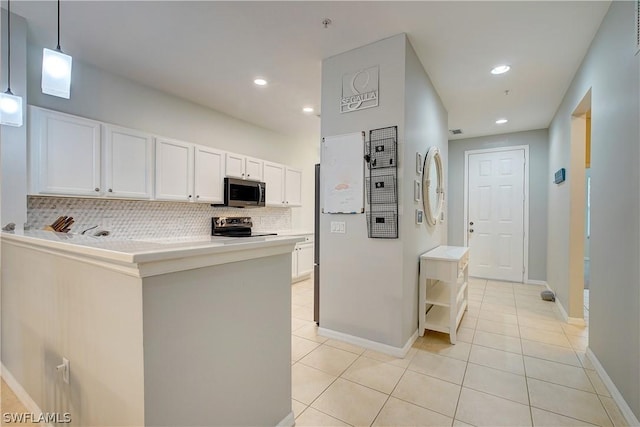 kitchen with light tile patterned flooring, appliances with stainless steel finishes, pendant lighting, white cabinets, and backsplash