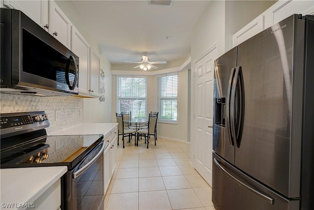 kitchen featuring stainless steel appliances, light tile patterned floors, and white cabinets