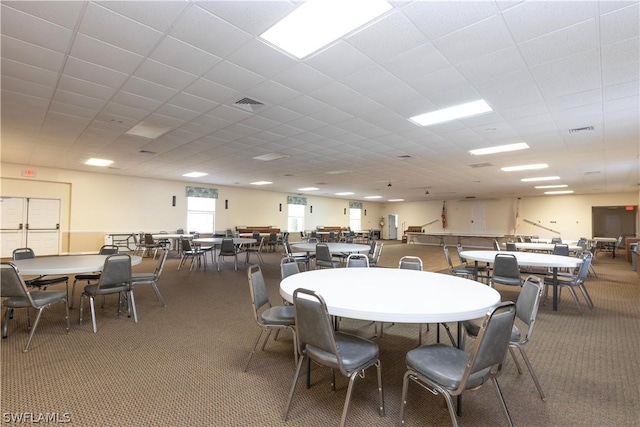 carpeted dining space featuring a drop ceiling