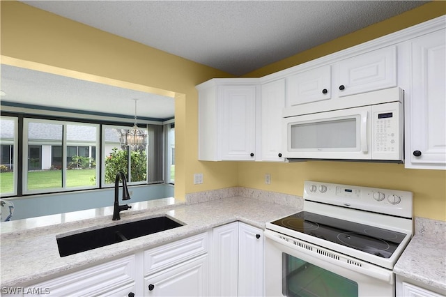 kitchen featuring sink, hanging light fixtures, a chandelier, white appliances, and white cabinets