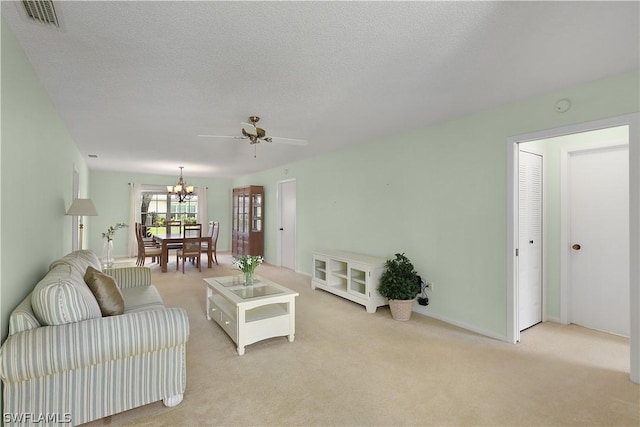 carpeted living room with a textured ceiling and ceiling fan with notable chandelier