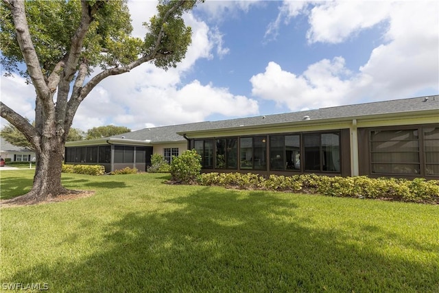 rear view of property featuring a lawn and a sunroom