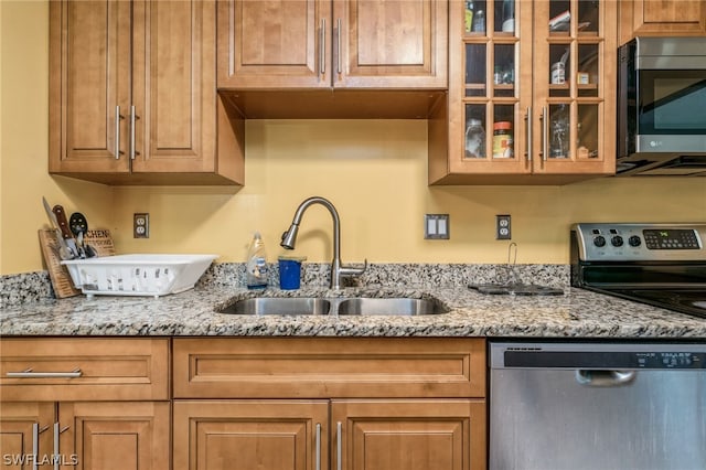 kitchen featuring sink, appliances with stainless steel finishes, and light stone counters