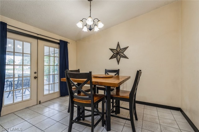 tiled dining room featuring french doors, a textured ceiling, and a chandelier