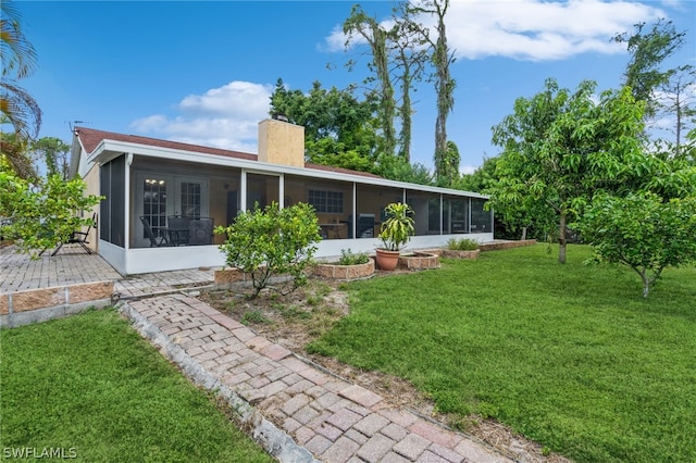 rear view of property with a yard and a sunroom