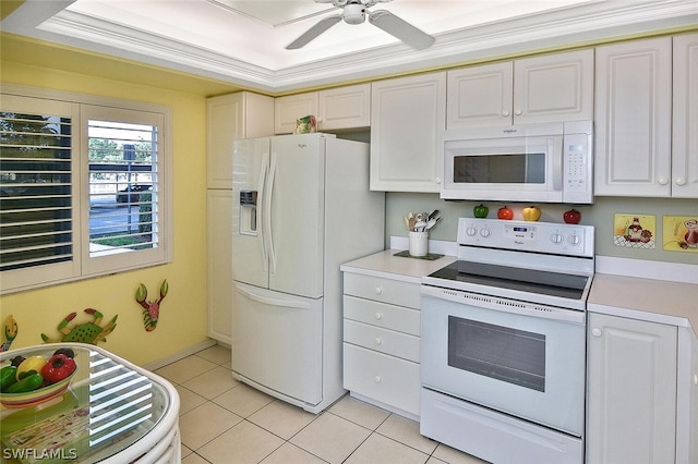 kitchen featuring white appliances, light tile patterned flooring, ceiling fan, a tray ceiling, and crown molding