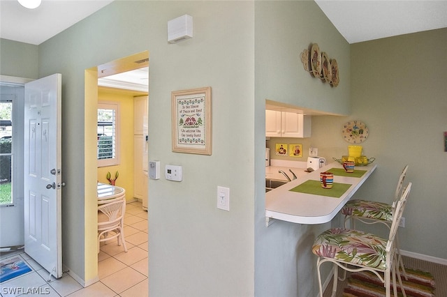 14931 Park Lake Dr Unit 109, Fort Myers, FL 33919 - kitchen featuring a kitchen bar, plenty of natural light, light tile patterned floors, and light countertops