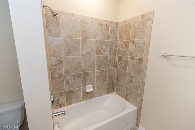 bathroom with toilet and tiled shower / bath