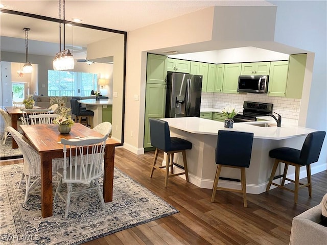 kitchen with tasteful backsplash, stainless steel appliances, a breakfast bar, and green cabinets