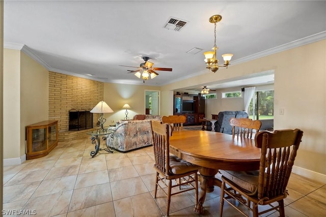 tiled dining area featuring ornamental molding, ceiling fan with notable chandelier, and a fireplace