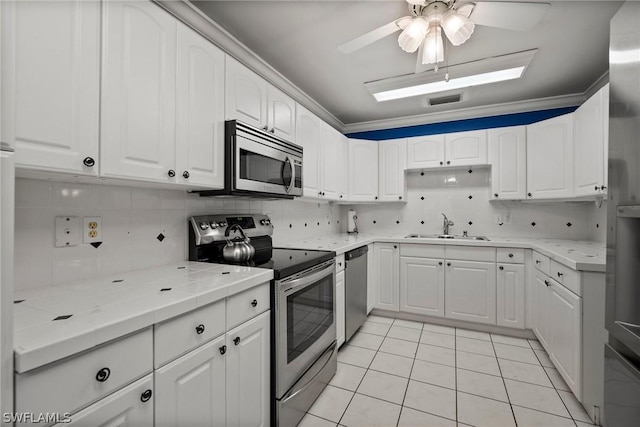 kitchen with sink, white cabinets, light tile patterned flooring, backsplash, and appliances with stainless steel finishes