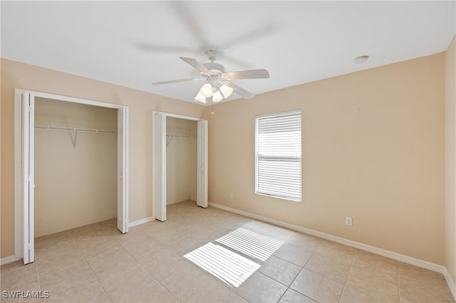 unfurnished bedroom featuring ceiling fan, multiple closets, and light tile patterned floors