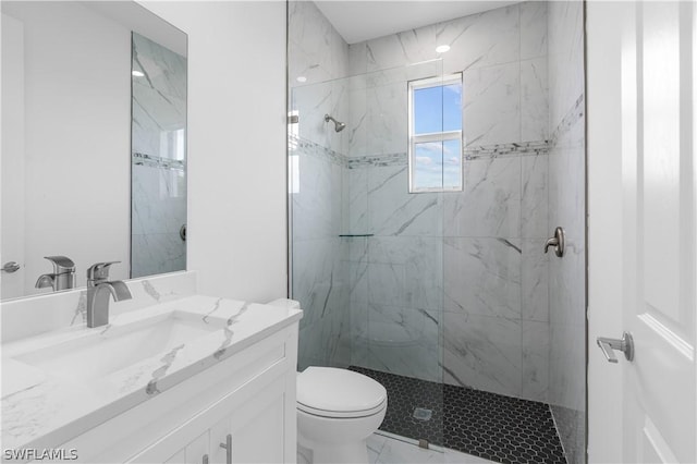 bathroom featuring a tile shower, vanity, and toilet