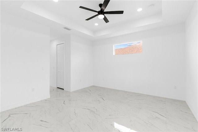 empty room featuring ceiling fan and a tray ceiling