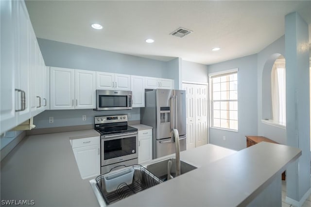 kitchen featuring kitchen peninsula, white cabinets, and stainless steel appliances