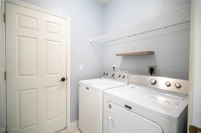 clothes washing area featuring washer and clothes dryer and light tile patterned floors