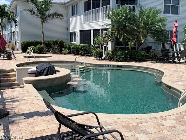 view of pool with a hot tub and a patio area