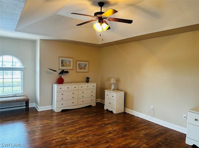 interior space with dark wood-type flooring, a tray ceiling, and ceiling fan