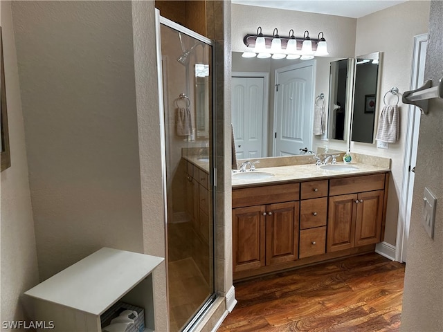 bathroom featuring double vanity, an enclosed shower, and wood-type flooring