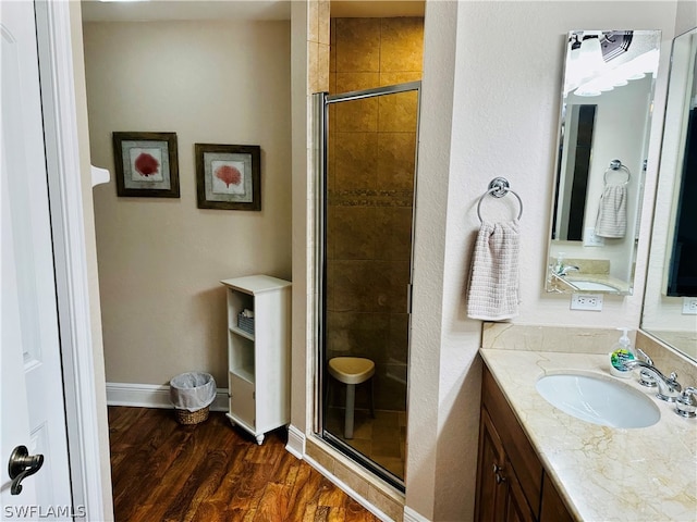 bathroom with a shower with shower door, vanity, and hardwood / wood-style floors