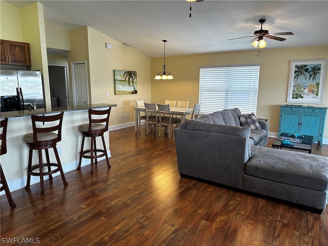 living room featuring dark hardwood / wood-style floors, ceiling fan with notable chandelier, and vaulted ceiling