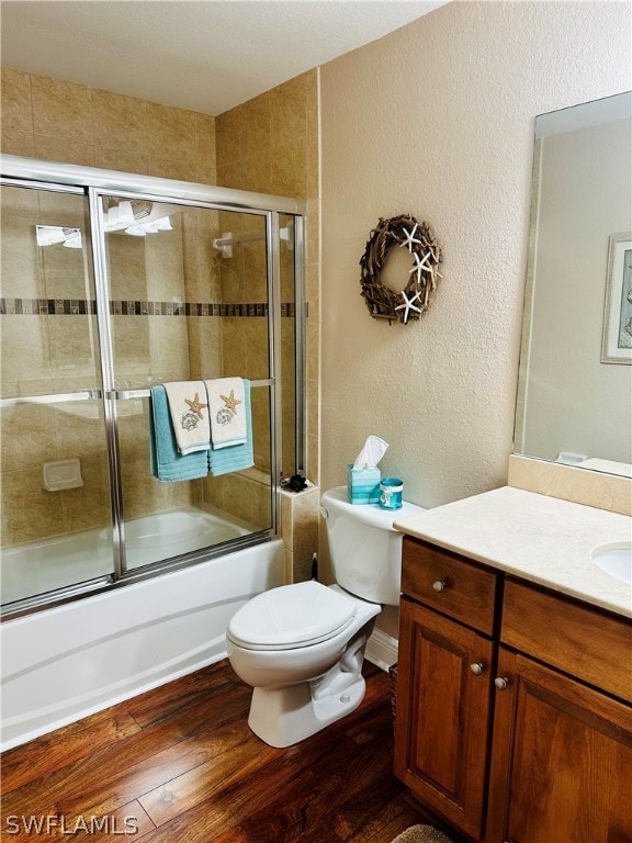 full bathroom with vanity, shower / bath combination with glass door, toilet, and hardwood / wood-style floors