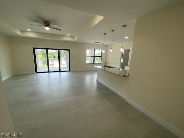 unfurnished room featuring tile flooring, ceiling fan, a raised ceiling, and sink