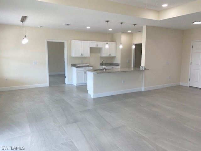 kitchen featuring dark stone countertops, sink, hanging light fixtures, and white cabinets