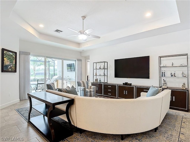 living room with a raised ceiling and ceiling fan