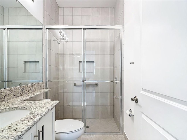 bathroom with a shower with door, vanity, and toilet