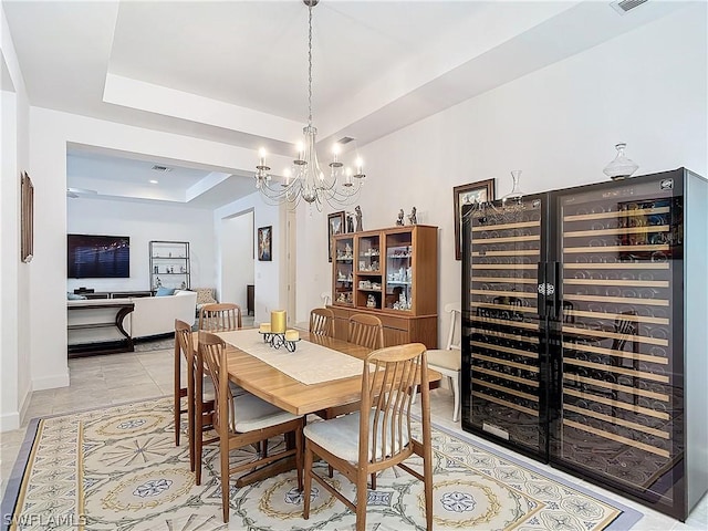 dining area featuring a chandelier, light tile patterned floors, wine cooler, and a tray ceiling