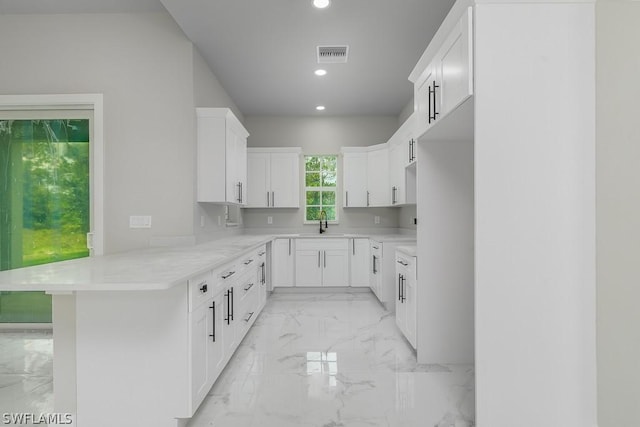 kitchen with white cabinetry, kitchen peninsula, and sink